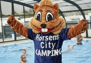 Mascotte en costume d’écureuil devant piscine couverte avec enfants à Horsens City Camping au Danemark.