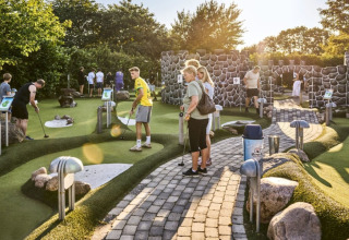 Mensen genieten van minigolf op een zonnige dag bij Horsens City Camp vakantiepark in Centraal-Denemarken.