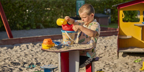 Dreng leger med sand i sandkassen ved Horsens City Camp, en populær feriepark i Midtjylland, Danmark.