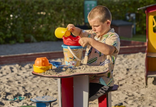 Dreng leger med sand i sandkassen ved Horsens City Camp, en populær feriepark i Midtjylland, Danmark.