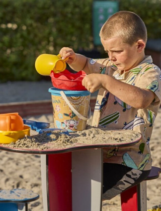 Jongen speelt met zand in de speeltuin van Horsens City Camp, een populair vakantiepark in Midden-Denemarken.
