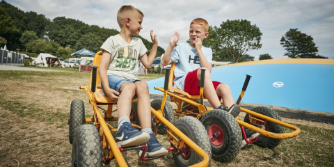 Two boys on go-karts give each other a high five at Horsens City Camp, a holiday park in Central Denmark.