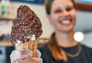 Woman smiling and holding a chocolate-sprinkled ice cream cone at Horsens City Camp in Denmark.