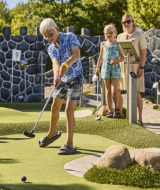 Gezin speelt minigolf bij Horsens City Camp, een vakantiepark in de regio Centraal-Denemarken.