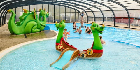 Bambini giocano in piscina coperta con scivolo a forma di drago all'Horsens City Camp in Danimarca.