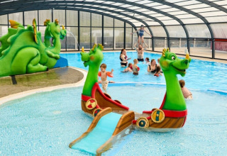 Children play in an indoor swimming pool with dragon-themed slide at Horsens City Camp, Denmark.