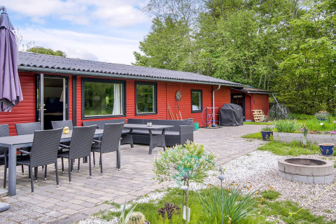 Area esterna della casa vacanze per 8 persone a Holbæk, Danimarca, con tavolo, sedie e braciere.