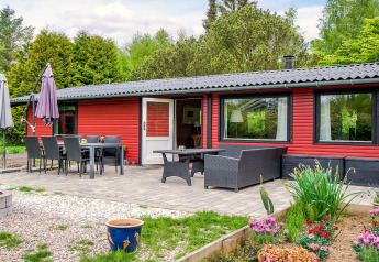 Terrasse avec salle à manger et salon extérieur devant une maison de vacances rouge à Holbæk, Danemark.