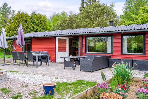 Patio con tavolo da pranzo e salotto all'aperto davanti a un alloggio rosso a Holbæk, Danimarca.