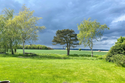 Vue depuis une maison de vacances 8 personnes à Holbæk, Danemark, sur champs verts et ciel nuageux.