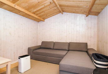 Gezellige woonkamer met grijze hoekbank, houten plafond, lichte houten muren en luchtreiniger.