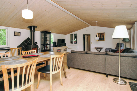 Stue i 8-personers feriehus i Holbæk, Danmark med spisebord, sofa, brændeovn og moderne indretning.