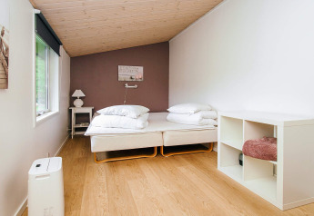 Lichte slaapkamer met twee eenpersoonsbedden en een kast in een vakantiehuis in Holbæk, Denemarken.
