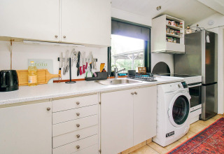 Moderne keuken in een vakantiehuis in Holbæk met witte kasten, wasmachine en koelkast.