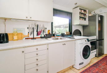 Moderne Küche in einem Ferienhaus in Holbæk mit weißen Schränken, Waschmaschine und Kühlschrank.