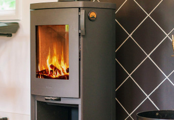 Poêle à bois moderne avec feu visible dans un gîte à Holbæk, Danemark, parfait pour l’hiver.