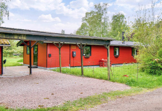 Maison de vacances rouge avec carport couvert et jardin verdoyant à Holbæk, Danemark, pour 8 personnes.