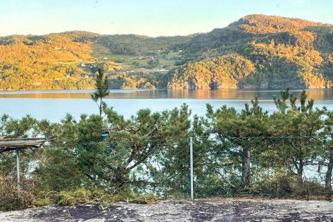 Vista da una casa vacanze a Hjelmeland in Danimarca con montagne, lago e luce del sole sul paesaggio.