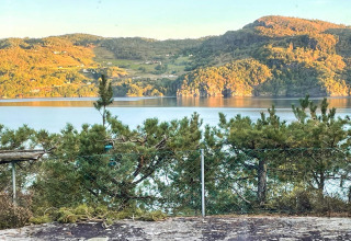 Vista da una casa vacanze a Hjelmeland in Danimarca con montagne, lago e luce del sole sul paesaggio.