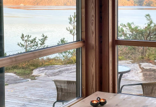 Udsigt fra et sommerhus i Hjelmeland, Danmark, med store vinduer, natur og sø i baggrunden.
