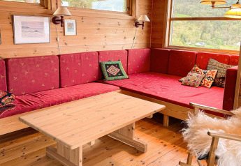 Gemütliche Sitzecke mit roten Polstern, Holztisch und Fenster im 7-Personen-Ferienhaus in Hjelmeland, Dänemark.