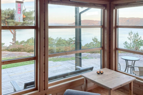 Vista dal soggiorno di una casa vacanze a Hjelmeland, Danimarca, con ampie finestre su lago e colline.