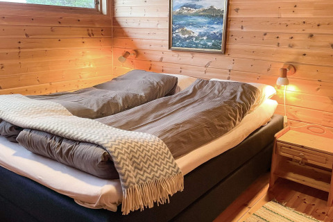 Dormitorio acogedor con cama doble y paredes de madera en una cabaña para 7 personas en Hjelmeland, Dinamarca.