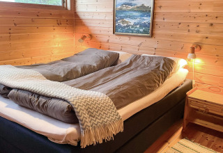 Dormitorio acogedor con cama doble y paredes de madera en una cabaña para 7 personas en Hjelmeland, Dinamarca.