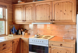 Houten keuken in een lodge in Hjelmeland met fornuis, kasten en raam, gezellige Deense sfeer.