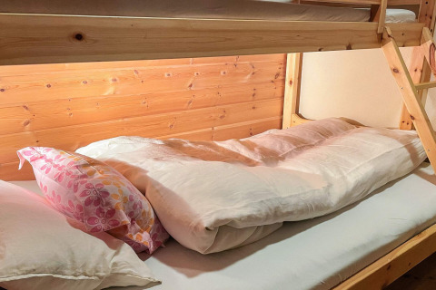 Holz-Etagenbett mit bunter Kissen und weißer Bettdecke in einem 7-Personen-Ferienhaus in Hjelmeland, Dänemark.