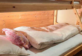 Holz-Etagenbett mit bunter Kissen und weißer Bettdecke in einem 7-Personen-Ferienhaus in Hjelmeland, Dänemark.