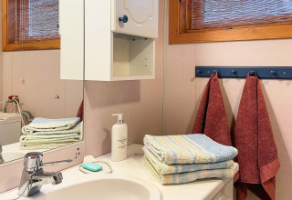 Badkamer in vakantiehuis in Hjelmeland, Denemarken, met handdoeken, zeep, lotion en spiegel.