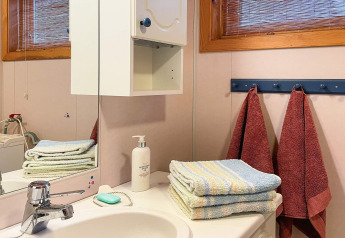 Badeværelse i feriehjem med håndklæder, sæbe, lotion og spejl på Hjelmeland-lodge i Danmark.