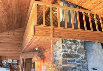 Intérieur d'une maison de vacances 7 personnes à Hjelmeland avec mezzanine, bois et cheminée en pierre.