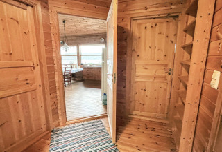 Indgang til en træbeklædt gang med tæppe, åbner op til en spisestue med udsigt, 7 personers feriehus i Hjelmeland.