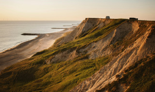 Kustkliffen en strand bij zonsondergang nabij Horsens, Denemarken, met groene hellingen langs de kust.