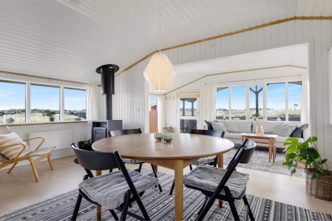 Helles, modernes Wohnzimmer eines Strandhauses in Lokken, Dänemark, mit großen Fenstern und Holzdekor.