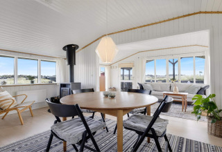 Espacioso y luminoso salón en casa de playa en Lokken, Dinamarca, con ventanales y decoración moderna.