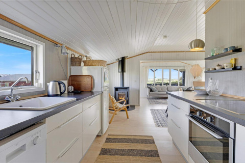 Cucina luminosa e soggiorno in casa sulla spiaggia a Lokken, Danimarca, con arredo moderno e vista mare.