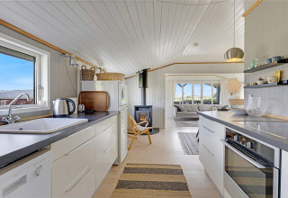 Lichte keuken en leefruimte in strandhuis te Lokken, Denemarken, met modern interieur en zicht op zee.