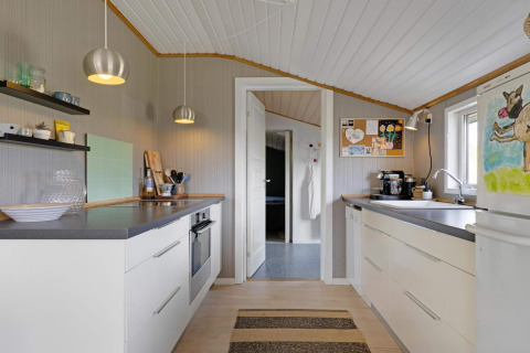 Cuisine moderne dans une maison de plage à Lokken, Danemark, avec armoires blanches et décoration chaleureuse.