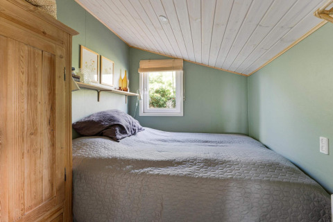 Gemütliches Schlafzimmer mit Holzmöbeln und Dachschräge in einem Strandhaus in Lokken, Dänemark.