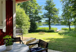 Udsigt fra terrasse ved 'Lakeside Cabin Retreat in Sollentuna' mod sø, træer og solrigt græsareal.