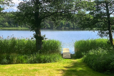 Blick auf einen See mit Steg und Bäumen bei der Lakeside Cabin Retreat in Sollentuna, Schweden.
