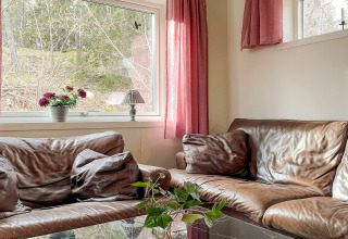Cozy Lakeside Cabin Retreat in Sollentuna, Sweden, with brown leather sofas, pillows and garden views.