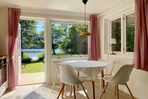 Coin repas lumineux dans un chalet au bord du lac à Sollentuna, Suède, vue sur la nature et l'eau.