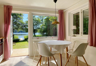 Luminoso comedor en cabaña junto al lago en Sollentuna, Suecia, con vistas a la naturaleza y al agua.