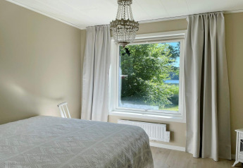 Chambre du Lakeside Cabin Retreat à Sollentuna, Suède, avec grande fenêtre et vue lac paisible.