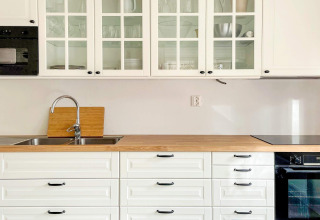 Cucina luminosa con mobili bianchi, piano in legno e ante in vetro al Lakeside Cabin Retreat a Sollentuna.