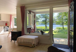 Accogliente soggiorno di un rifugio sul lago a Sollentuna, Svezia, con grandi finestre sul lago verde.